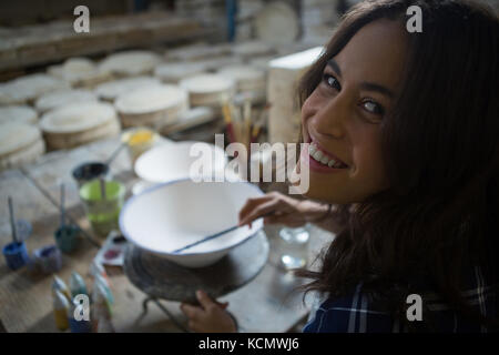 Portrait de femme peinture potter bol dans atelier de poterie Banque D'Images