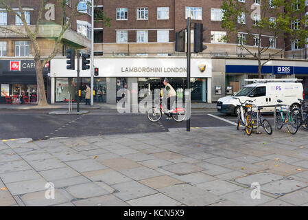 Un homme sur un vélo Santander après le concessionnaire Lamborghini showroom à South Kensington, London, UK Banque D'Images