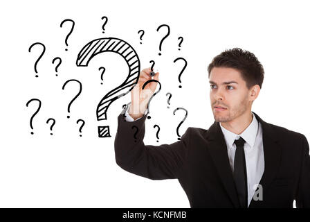 L'homme écrit beaucoup de questions sur l'écran blanc Banque D'Images