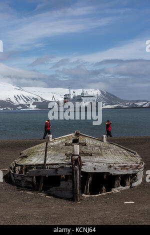 Les touristes d'aventure à pied près de l'eau de bateaux abandonnés depuis longtemps l'ère de la chasse à la baleine sur une plage volcanique à la baie des baleiniers, Deception Island, îles Shetland du Sud Banque D'Images