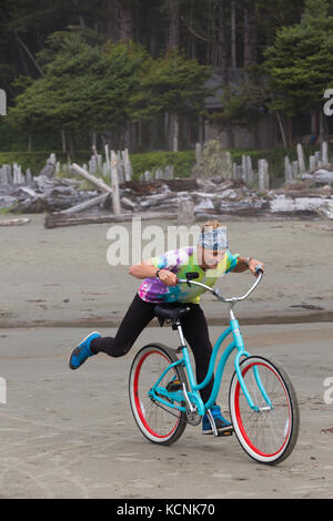 Un cavalier avec un tie dye t-shirt joue sur son beach cruiser alors que sur Chesterman Beach. Tofino, Vancouver Island, British Columbia, Canada. Banque D'Images