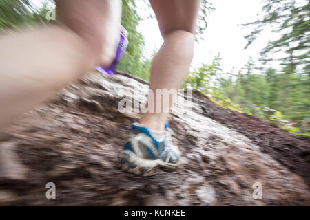 Les jambes d'une femme en marche sur le sentier boueux, à Courtenay, Colombie-Britannique, Canada Banque D'Images