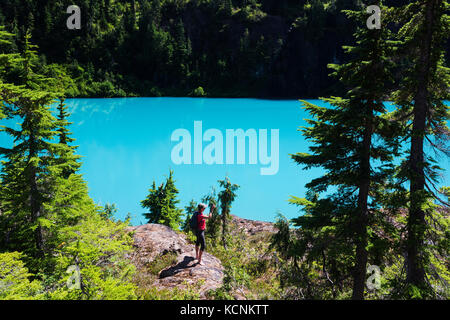 Un randonneur femelle s'arrête pour apprécier la vue sur un rocher falaise donnant sur le lac, sam siècle parc Strathcona, l'île de Vancouver, Colombie-Britannique, Canada Banque D'Images