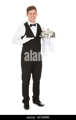 Waiter holding empty silver tray sur fond blanc Banque D'Images