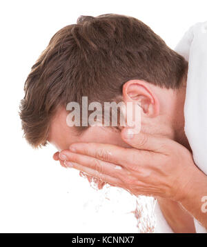 Jeune homme beau laver son visage isolé sur fond blanc Banque D'Images