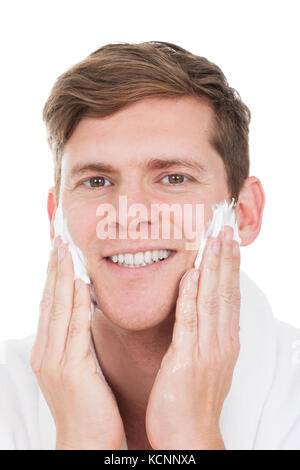 Happy Young Man Applying Shaving Cream isolé sur fond blanc Banque D'Images