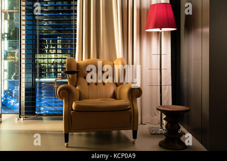 Fauteuil en cuir, table basse et lampe de plancher dans le hall de l'hôtel. design intérieur de cuir classique chaise et lampe en pièce sombre. Banque D'Images