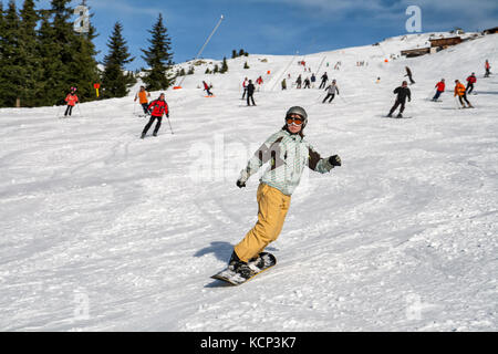 Jeune fille sur une planche à neige vers le bas sur l'arrière-plan d'une longue pente de ski Banque D'Images