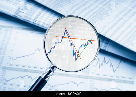 Loupe montre une action. à l'arrière-plan des tables de taux et des graphiques peuvent être vus. Banque D'Images