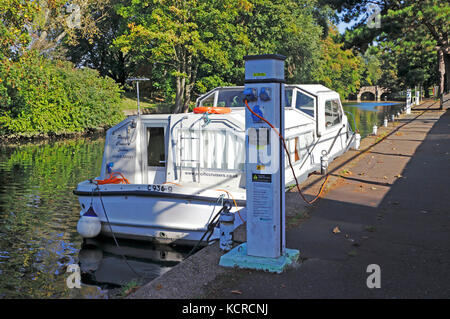 Un croiseur amarré à Riverside sur la rivière Wensum et relié à un point de service à Norwich, Norfolk, Angleterre, Royaume-Uni. Banque D'Images