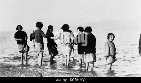 Cette photographie capture des enfants réfugiés grecs et arméniens dans la mer près de Marathon, en Grèce, vers 1915, illustrant le sort des réfugiés pendant la première Guerre mondiale. Elle souligne les difficultés et les déplacements auxquels sont confrontés les enfants pendant cette période. Banque D'Images