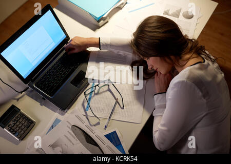 Tired woman sleeping on table office de nuit Banque D'Images