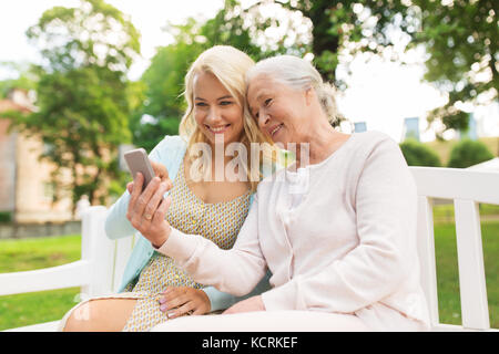 Fille et mère senior avec smartphone at park Banque D'Images