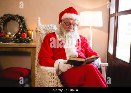 Père Noël roman lecture dans la salle de séjour pendant la période de Noël Banque D'Images