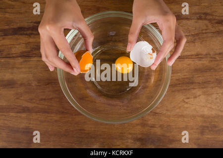 La mi-section de l'homme casser des œufs dans un bol Banque D'Images