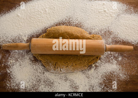 Plus de head voir d'aplatissement de pâte avec un rouleau à pâtisserie avec saupoudré sur la farine sur une table en bois Banque D'Images