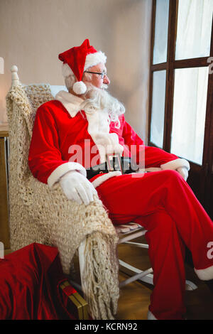 Le père Noël à la recherche à travers une fenêtre dans salle de séjour pendant la période de Noël Banque D'Images