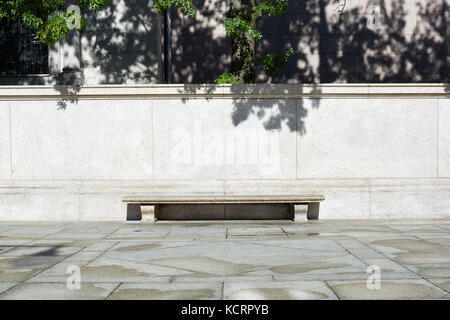 Banc de pierre vide avec fond noir en lumière les feuilles des arbres et les ombres dans une journée ensoleillée Banque D'Images