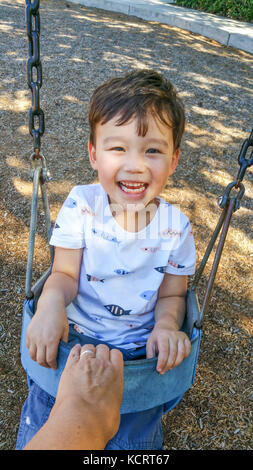 Portrait Chinois et adorable jeune garçon s'amusant dans l'oscillation. Banque D'Images