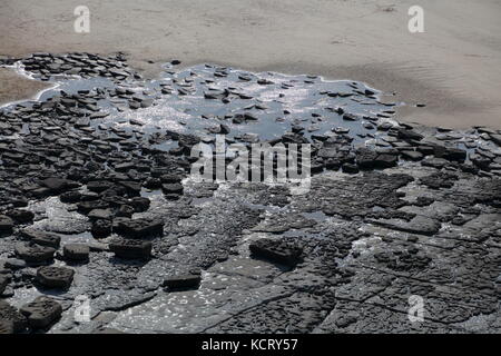 À la recherche vers le bas sur la plage de la baie de Dunraven, avec ses divers black rocos parsemées autour de la plage assis sur d'autres couches de roche.