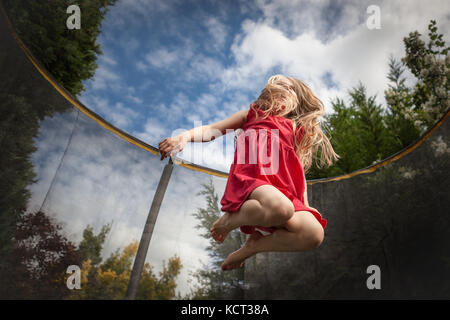 Girl jumping on trampoline Banque D'Images