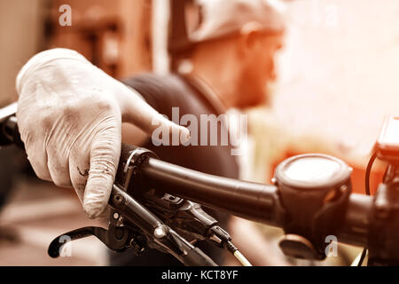 Les mains dans les gants sur le guidon de vélo cycle fixation mécanique. dans son atelier. photo gros plan Banque D'Images