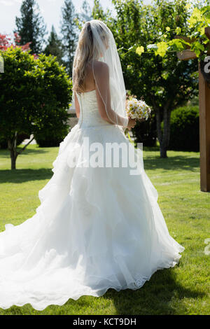 Mariée avec fleurs standing in park on a sunny day Banque D'Images