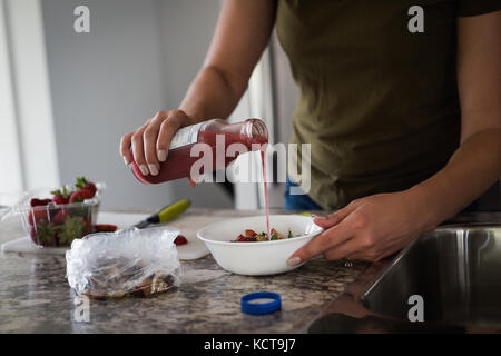 Mid section of woman pouring en sirop de fraises hachées à la maison Banque D'Images