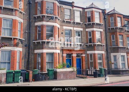 Façade d'un immeuble d'habitation restaurée de style victorien en briques rouges et jaunes avec des fenêtres en baie classique et bleu portes avant. Banque D'Images