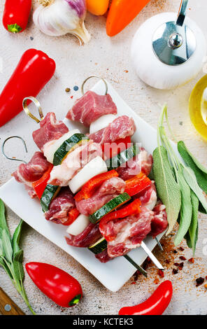 Kebab cru avec des légumes sur plaque et sur une table Banque D'Images