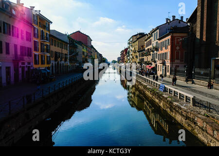 Vue panoramique sur le quartier naviglio grande bondé à Milan avec de l'eau réflexions et sun flare purple against blue sky Banque D'Images