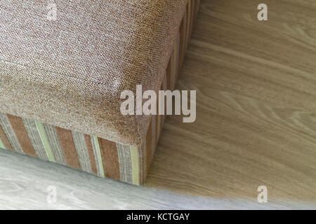 Détail d'un beige moderne canapé texturés dans la salle de séjour sur parquet stratifié en bois. Banque D'Images