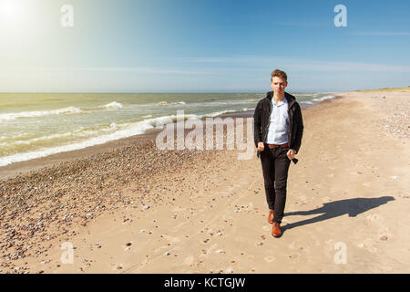 Un homme marchant le long d'une plage vide Banque D'Images