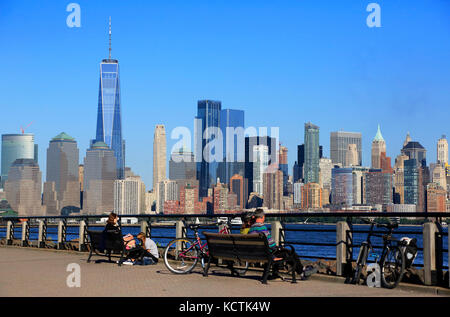 Les visiteurs se détendent sur la passerelle du bord de mer de l'Hudson avec vue sur Lower Manhattan en arrière-plan.New York City/New Jersey, États-Unis Banque D'Images