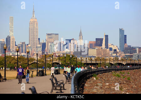 Visiteurs à la promenade du bord de mer de Hudson River dans le parc national Liberty avec le centre-ville de Manhattan à New York et l'Empire State Building en arrière-plan.NJ.USA Banque D'Images