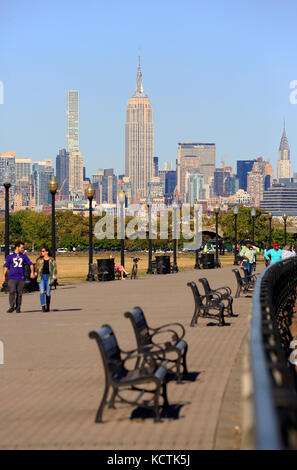 Visiteurs à la promenade du bord de mer de Hudson River dans le parc national Liberty avec le centre-ville de Manhattan à New York et l'Empire State Building en arrière-plan.NJ.USA Banque D'Images