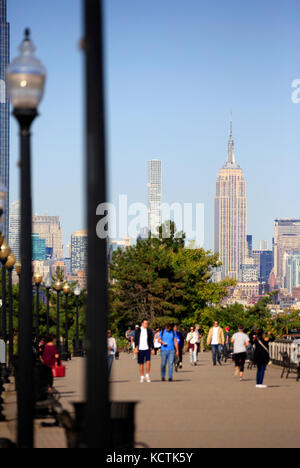 Visiteurs à la promenade du bord de mer de Hudson River dans le parc national Liberty avec le centre-ville de Manhattan à New York et l'Empire State Building en arrière-plan.NJ.USA Banque D'Images