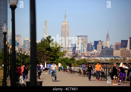 Visiteurs à la promenade du bord de mer de Hudson River dans le parc national Liberty avec le centre-ville de Manhattan à New York et l'Empire State Building en arrière-plan.NJ.USA Banque D'Images