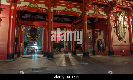 Image horizontale de porte d'entrée du temple Sensoji tourné la nuit avec de grandes lanternes, colonnes rouges et les ombres floues et touristes sous des lanternes. Banque D'Images
