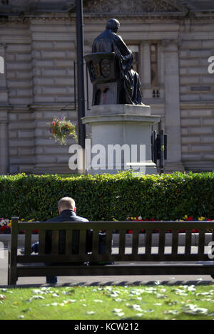 Assis om un banc regarder la vie aller par les touristes George Square Glasgow Banque D'Images