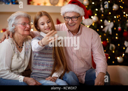 Heureux moments en famille -petite-fille souriante avec smartphone prendre selfies Banque D'Images