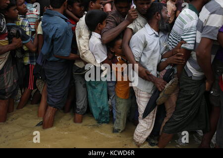 Peuple rohingya s'efforcent de l'avant dans une rangée, lorsqu'ils attendent une balikhali secours près de camp de réfugiés. Banque D'Images