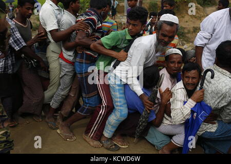 Peuple rohingya s'efforcent de l'avant dans une rangée, lorsqu'ils attendent une balikhali secours près de camp de réfugiés. Banque D'Images