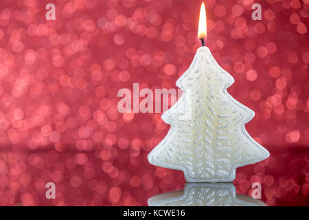 La lumière des bougies de l'arbre de Noël avec la réflexion sur l'arrière-plan flou floue rouge. Banque D'Images