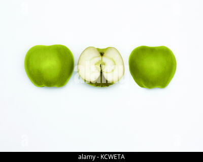 La pomme verte Granny Smith frais Vue de dessus trois moitiés de pomme verte sont couchées horizontalement dans une rangée sur un fond blanc Banque D'Images