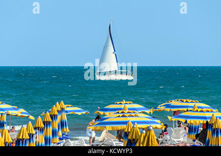 Albena, Bulgarie - 17 juin 2017 : le vent voile yacht sur bleu noir l'eau de mer près de plage avec les touristes Banque D'Images