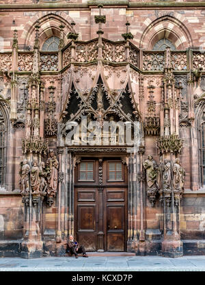 Porte nord de la cathédrale de Strasbourg avec mendiant assis sur les marches Banque D'Images