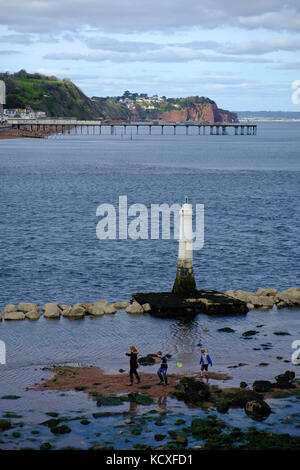 Enfants jouant avec un filet de pêche dans des bassins de roche à l'entrée de la rivière Teign depuis Shaldon, en regardant de l'autre côté de la jetée à Teignmouth, Royaume-Uni Banque D'Images