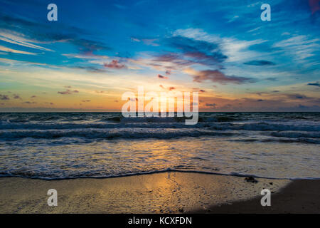 Ciel bleu au-dessus le soleil se lever sur l'horizon et qui se reflète sur l'eau sur un matin de grand vent à la plage Banque D'Images