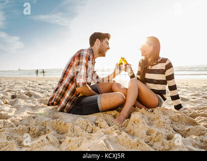 Jeune couple à la plage s'amuser, rire et boire de la bière Banque D'Images